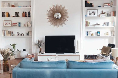 Cette image montre un salon design de taille moyenne et fermé avec une bibliothèque ou un coin lecture, un mur blanc, un sol en bois brun et un sol marron.