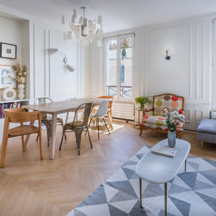 Réalisation d'un salon bohème ouvert avec un mur blanc, un sol en bois clair, un sol beige et du lambris.