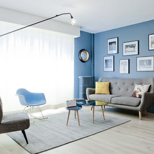 Cette image montre un salon vintage de taille moyenne et fermé avec une salle de réception, un mur bleu, un sol en bois clair, aucune cheminée et aucun téléviseur.