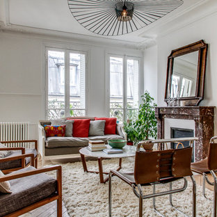 Réalisation d'un salon tradition ouvert et haussmannien avec une salle de réception, un mur blanc, un sol en bois clair, une cheminée standard, aucun téléviseur et un sol beige.