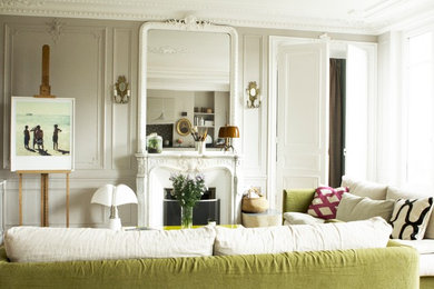 パリにあるお手頃価格の中くらいなエクレクティックスタイルのおしゃれなLDK (白い壁、淡色無垢フローリング、標準型暖炉、石材の暖炉まわり、テレビなし、茶色い床) の写真