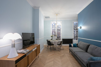 Modelo de salón abierto tradicional renovado de tamaño medio con paredes azules, suelo de contrachapado, televisor independiente y suelo beige