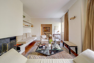 Ejemplo de salón para visitas abierto actual grande con paredes beige, suelo de madera en tonos medios, chimenea lineal y marco de chimenea de yeso