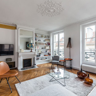 Inspiration pour un salon avec une bibliothèque ou un coin lecture traditionnel de taille moyenne et ouvert avec un mur blanc, un sol en bois brun, une cheminée standard, un téléviseur encastré et un manteau de cheminée en béton.