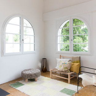 Cette image montre un salon vintage avec un mur blanc, un sol en liège, un poêle à bois et un manteau de cheminée en métal.