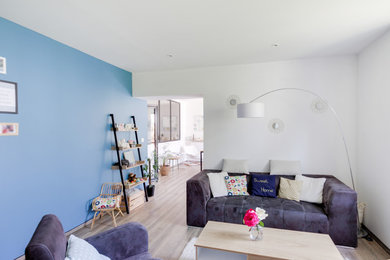 Réalisation d'un salon nordique de taille moyenne et ouvert avec un mur bleu, parquet clair, aucune cheminée, un téléviseur indépendant et un sol marron.