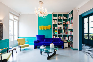 Aménagement d'un salon éclectique ouvert et de taille moyenne avec un mur bleu, un sol gris, une bibliothèque ou un coin lecture, sol en béton ciré, aucune cheminée et aucun téléviseur.