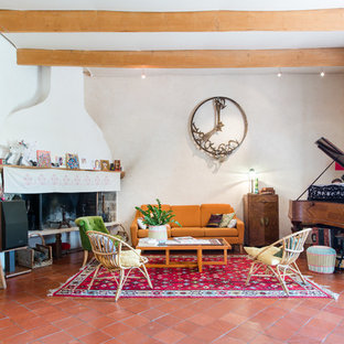 Aménagement d'un salon éclectique avec une salle de réception, un mur blanc, un sol en carreau de terre cuite, une cheminée d'angle, aucun téléviseur et un sol rouge.