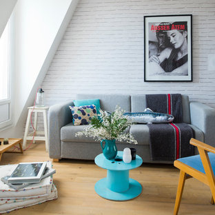 Idée de décoration pour un salon avec une bibliothèque ou un coin lecture design de taille moyenne avec un mur blanc, un sol en bois clair, aucune cheminée et aucun téléviseur.
