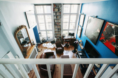 Diseño de biblioteca en casa abierta tradicional renovada pequeña con paredes azules, suelo de madera oscura y televisor colgado en la pared