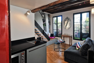 Mittelgroßes, Offenes Modernes Wohnzimmer mit weißer Wandfarbe, braunem Holzboden, freistehendem TV und braunem Boden in Paris
