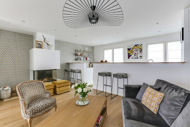Cette photo montre un salon scandinave de taille moyenne et ouvert avec un mur multicolore, une cheminée standard, parquet clair et un téléviseur indépendant.