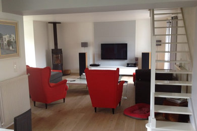 Exemple d'un salon tendance de taille moyenne et ouvert avec un mur blanc, parquet clair, un poêle à bois et un téléviseur fixé au mur.