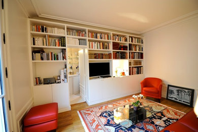 Источник вдохновения для домашнего уюта: гостиная комната среднего размера в современном стиле с с книжными шкафами и полками, белыми стенами, светлым паркетным полом, мультимедийным центром и бежевым полом без камина