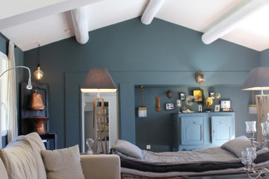 Idée de décoration pour un très grand salon mansardé ou avec mezzanine bohème avec un mur bleu, tomettes au sol, une cheminée standard, un manteau de cheminée en pierre, aucun téléviseur et un sol marron.