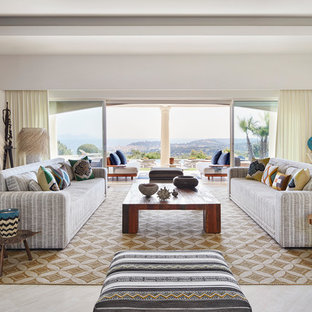 Réalisation d'un très grand salon marin ouvert avec une salle de réception, un mur blanc, un sol en travertin et un sol beige.