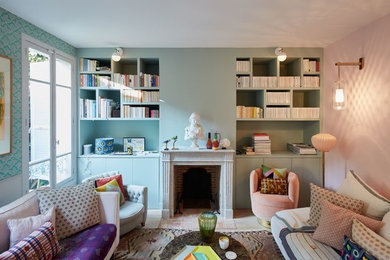Cette photo montre un salon chic avec une bibliothèque ou un coin lecture, un mur multicolore, une cheminée standard, un manteau de cheminée en brique, aucun téléviseur et éclairage.