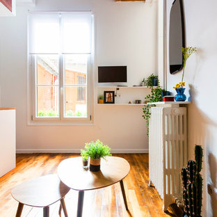 Idées déco pour un petit salon mansardé ou avec mezzanine industriel avec un mur blanc, un sol en bois brun, un sol marron, aucune cheminée et un téléviseur fixé au mur.