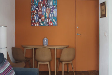 Aménagement d'un salon moderne avec un mur orange, sol en stratifié et un sol marron.