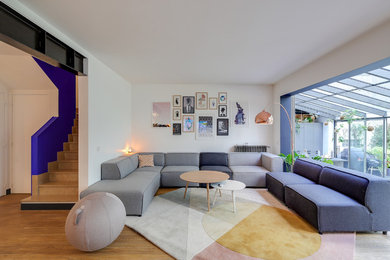 Cette image montre un grand salon minimaliste ouvert avec une salle de réception, un mur blanc et parquet clair.
