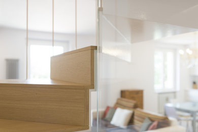 Immagine di una scala design con pedata in legno, parapetto in vetro e alzata in legno