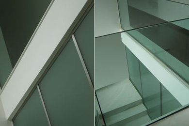 他の地域にある中くらいなコンテンポラリースタイルのおしゃれな折り返し階段 (大理石の蹴込み板、ガラスフェンス) の写真
