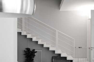 Diseño de escalera suspendida actual de tamaño medio con escalones de metal, contrahuellas de metal y barandilla de metal