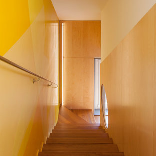 Immagine di una scala a "L" design di medie dimensioni con pedata in legno, parapetto in metallo e pareti in legno