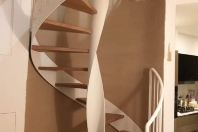 Imagen de escalera de caracol contemporánea sin contrahuella con escalones de madera y barandilla de metal