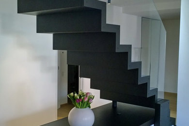 Ejemplo de escalera en L contemporánea con escalones de metal, contrahuellas de metal y barandilla de vidrio