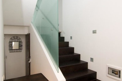Diseño de escalera en U actual con escalones de madera, contrahuellas de madera y barandilla de vidrio