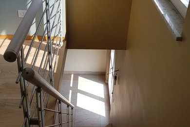 Diseño de escalera recta minimalista de tamaño medio con escalones de madera pintada, contrahuellas de madera pintada y barandilla de varios materiales