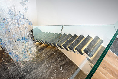 Ispirazione per una scala a rampa dritta contemporanea di medie dimensioni con pedata in marmo e parapetto in vetro