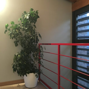 Immagine di una grande scala a "U" minimal con pedata in pietra calcarea, alzata in cemento e parapetto in metallo
