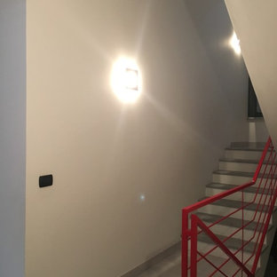 Idee per una grande scala a "U" minimal con pedata in pietra calcarea, alzata in cemento e parapetto in metallo