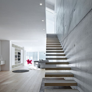 Foto di una grande scala sospesa minimalista con pedata in legno e nessuna alzata