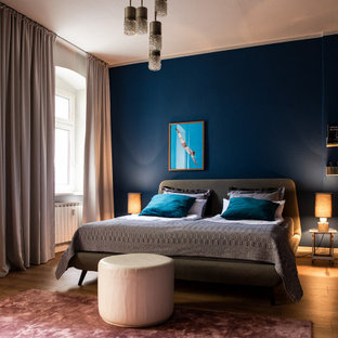 Immagine di una camera da letto eclettica di medie dimensioni con pareti blu, pavimento in legno verniciato e pavimento marrone