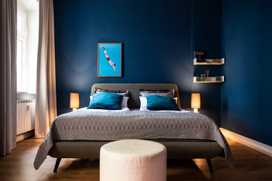 Mittelgroßes Stilmix Schlafzimmer mit blauer Wandfarbe, gebeiztem Holzboden und braunem Boden in Berlin