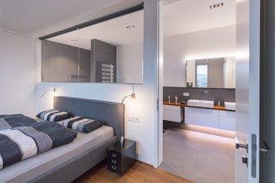 Mittelgroßes Modernes Hauptschlafzimmer ohne Kamin mit weißer Wandfarbe, braunem Holzboden und braunem Boden in Sonstige