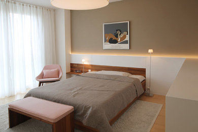 Modelo de dormitorio principal actual de tamaño medio con paredes marrones, suelo de madera en tonos medios y suelo beige