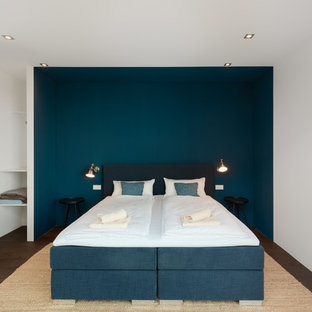 Mittelgroßes Modernes Gästezimmer ohne Kamin mit blauer Wandfarbe, dunklem Holzboden und braunem Boden in München
