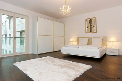 Geräumiges Klassisches Hauptschlafzimmer mit weißer Wandfarbe und dunklem Holzboden in Berlin