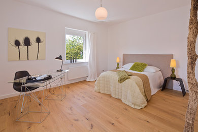 Großes Modernes Schlafzimmer ohne Kamin mit weißer Wandfarbe und braunem Holzboden in Frankfurt am Main
