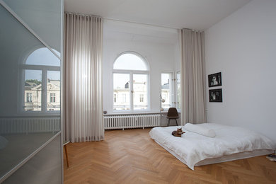 Пример оригинального дизайна: большая хозяйская спальня на мансарде в стиле модернизм с белыми стенами и паркетным полом среднего тона