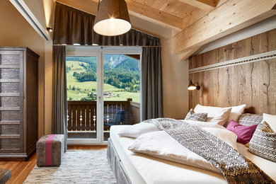 Ejemplo de dormitorio rural con paredes marrones y suelo de madera en tonos medios