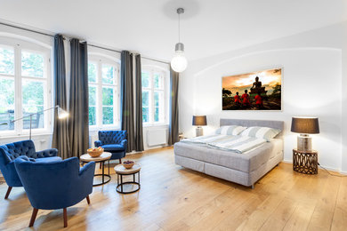 Großes Stilmix Schlafzimmer ohne Kamin mit weißer Wandfarbe und braunem Holzboden in Sonstige