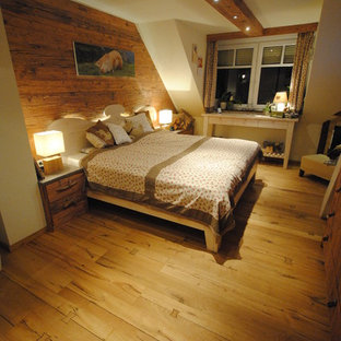 Imagen de dormitorio principal, rústico, de tamaño medio, con paredes blancas, suelo de madera clara y chimenea de esquina