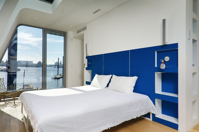 Imagen de dormitorio principal marinero de tamaño medio sin chimenea con paredes azules y suelo de madera en tonos medios