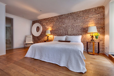 Cette image montre une grande chambre design avec un mur blanc, un sol en bois brun et aucune cheminée.