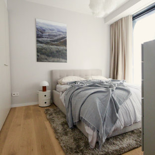 Modernes Schlafzimmer mit grauer Wandfarbe, braunem Holzboden und braunem Boden in Frankfurt am Main